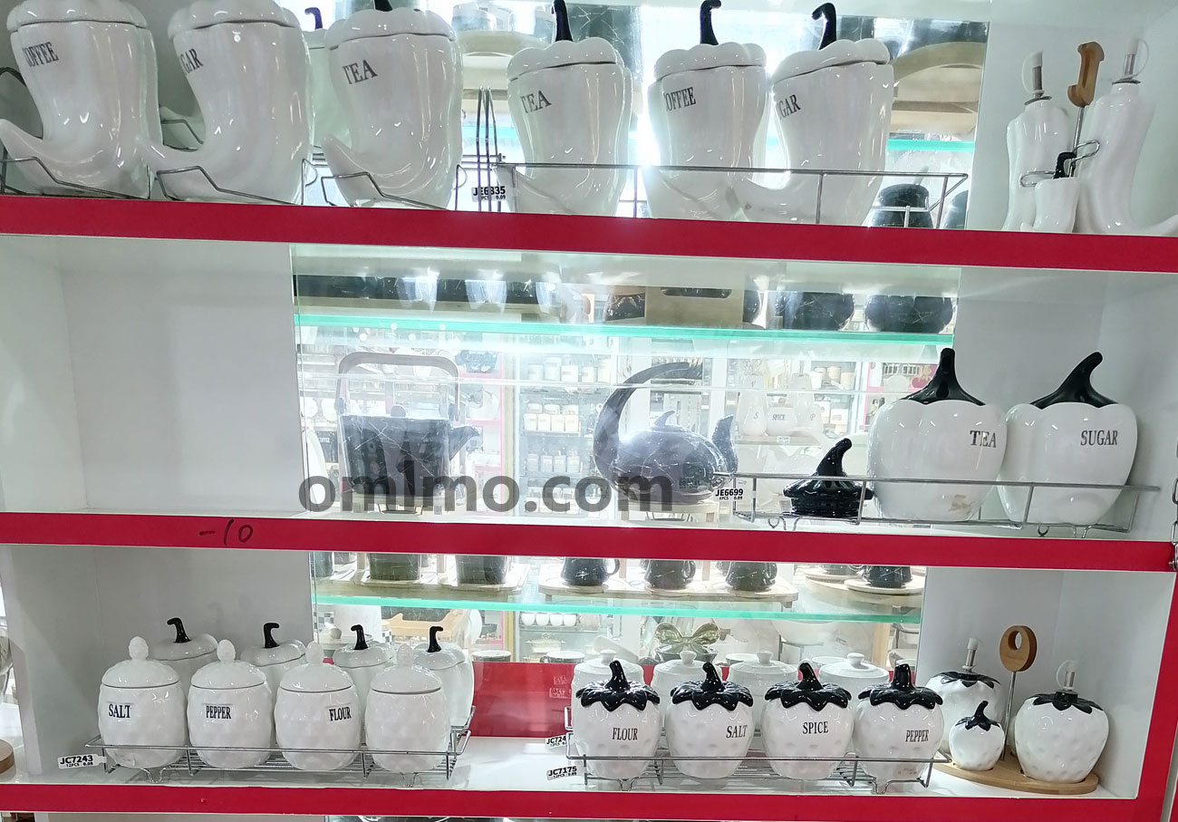 White ceramic pumpkin-shaped canister sets with COFFEE SUGAR TEA SALT PEPPER FLOUR SPICE labels in smooth and quilted textures on 3-shelf display